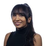 A woman with long dark hair and bangs, wearing a sleeveless black turtleneck, smiles while facing the camera against a plain white background.