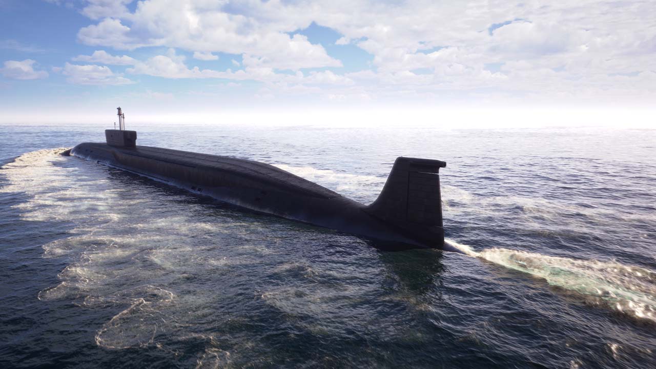 A large submarine travels on the surface of the ocean under a partly cloudy sky, creating a wake in the water behind it.