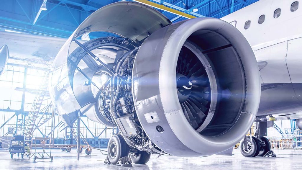 A close-up view of a commercial airplane engine being serviced in a brightly lit hangar, with the engine cover open and visible maintenance equipment around—showcasing the expertise found in our energy and utilities roles.