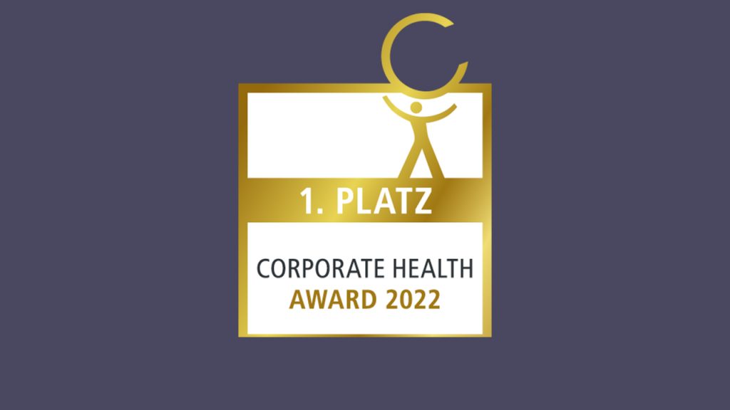 Gold and white award graphic with a stylized human figure holding a large "C." Text reads "1. Platz Corporate Health Award 2022" against a dark background.